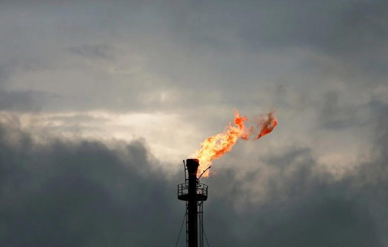 Gas flare stack burning against a cloudy sky