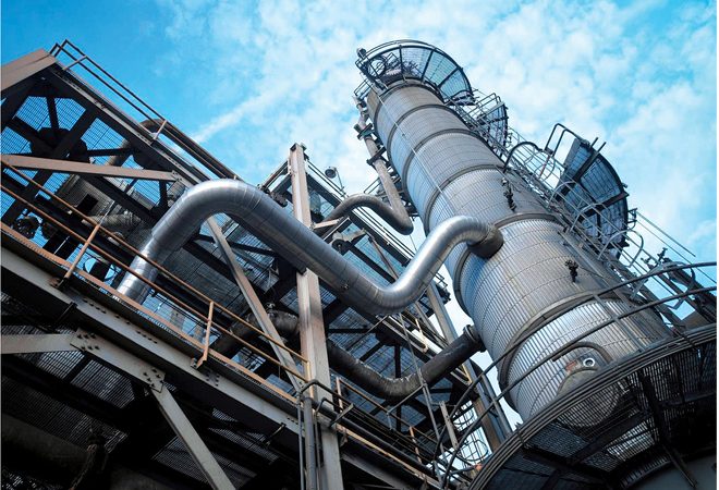 View from below of a combined-cycle gas turbine stack against a blue sky