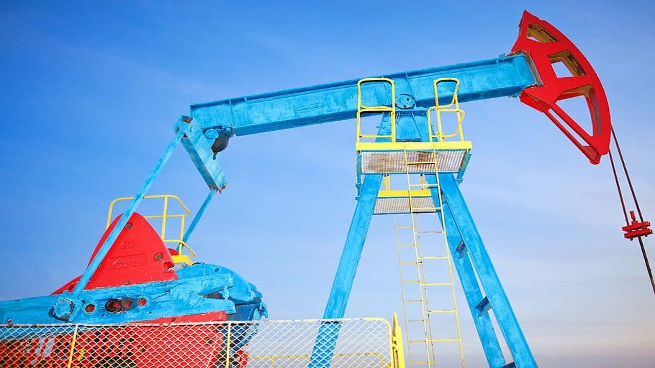 Blue and red oil pump jack against a clear sky